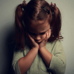 A sad girl holds her head in her hands