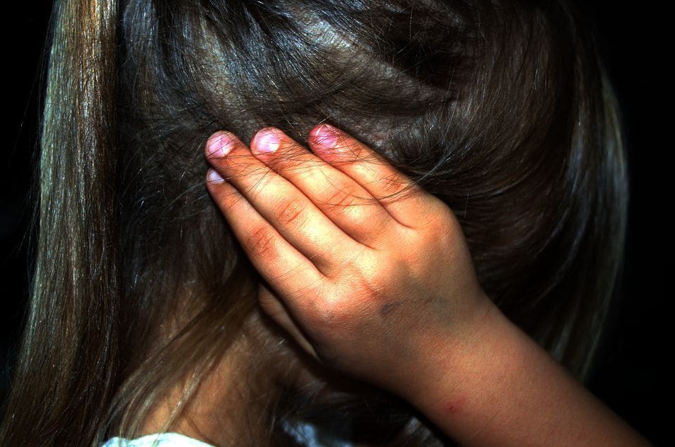 A young girl with CDV clasps her ears